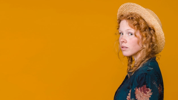 Hembra atractiva joven en la presentación del sombrero y del vestido