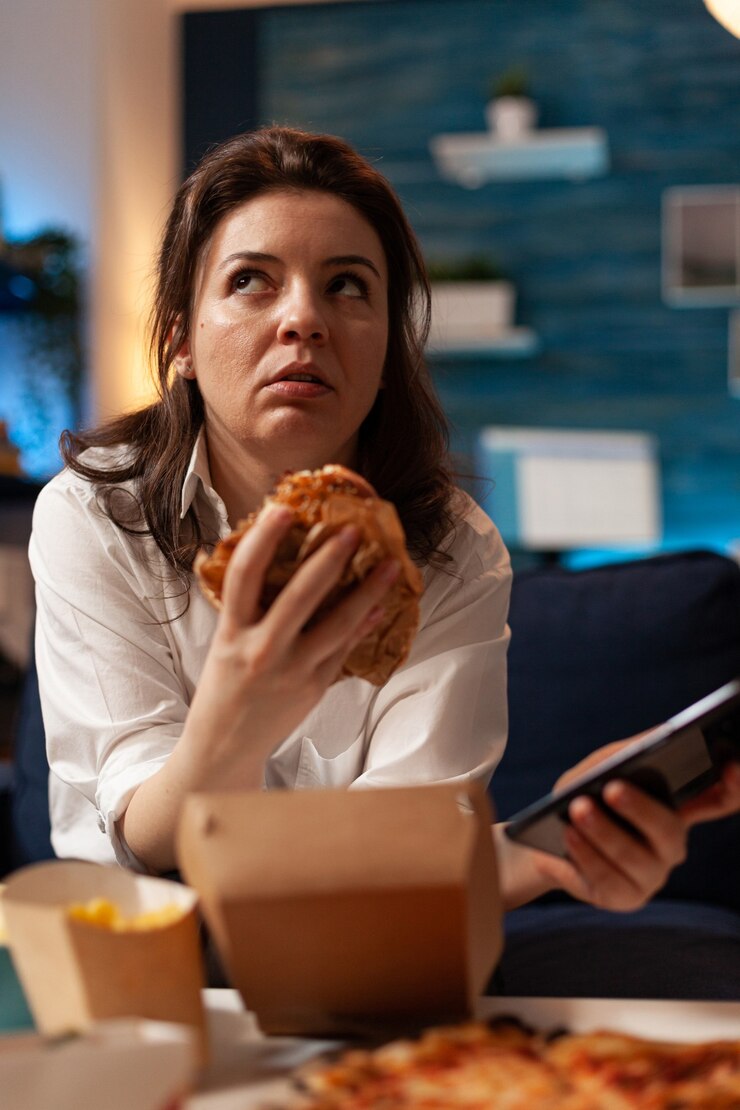 Foto gratuito hembra caucásica sosteniendo tastu burgery en manos navegando en las redes sociales con smartphone