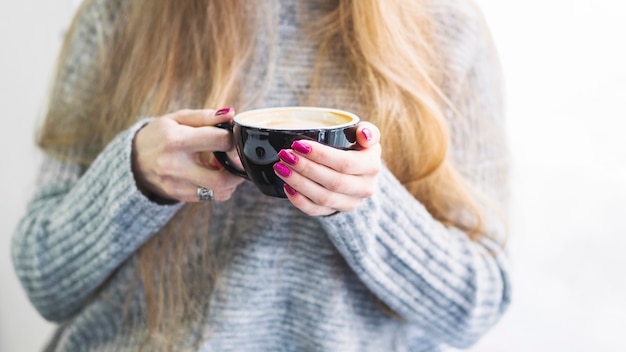 Hembra de cultivo en suéter con taza de café