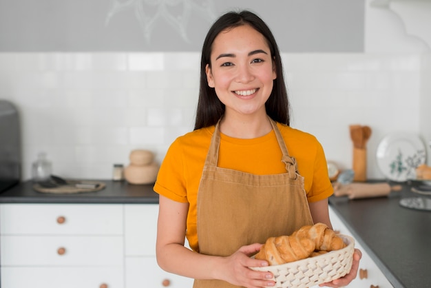 Hembra con delantal con cesta de croissant