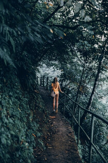 Hembra joven con barba y mochila posando en la selva.