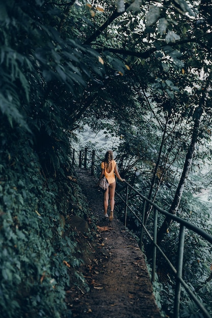 Hembra joven con barba y mochila posando en la selva.