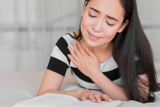 Hembra joven en la cama leyendo