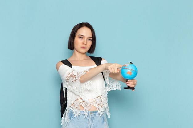 Hembra joven con camisa blanca y bolso negro sosteniendo un pequeño globo en azul