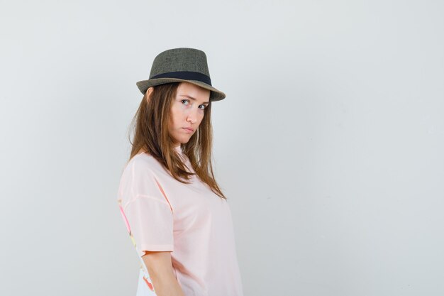 Hembra joven en camiseta rosa, sombrero y mirada triste.