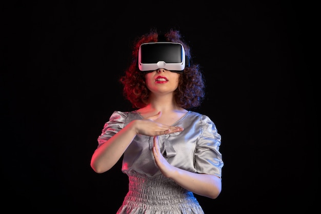 Hembra joven con casco de realidad virtual en la superficie oscura