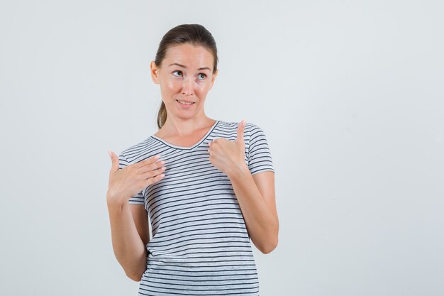 Hembra joven cogidos de la mano en gesto de interrogación en vista frontal de la camiseta rayada.