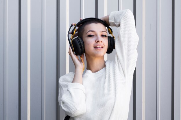 Hembra joven coqueta con cabeza rapada con auriculares