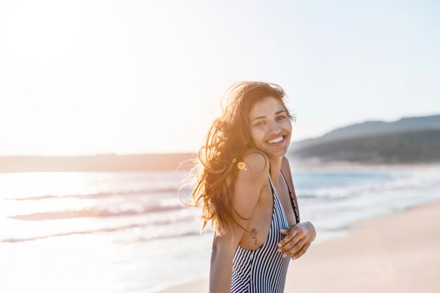 Hembra joven feliz en sol en la playa tropical