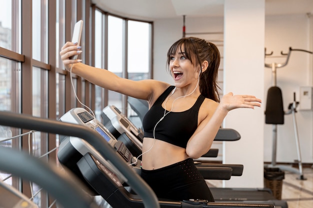 Hembra joven en el gimnasio tomando selfies