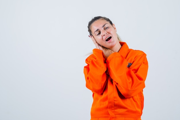 Hembra joven haciendo pucheros con los labios en uniforme de trabajador y luciendo extraña, vista frontal.