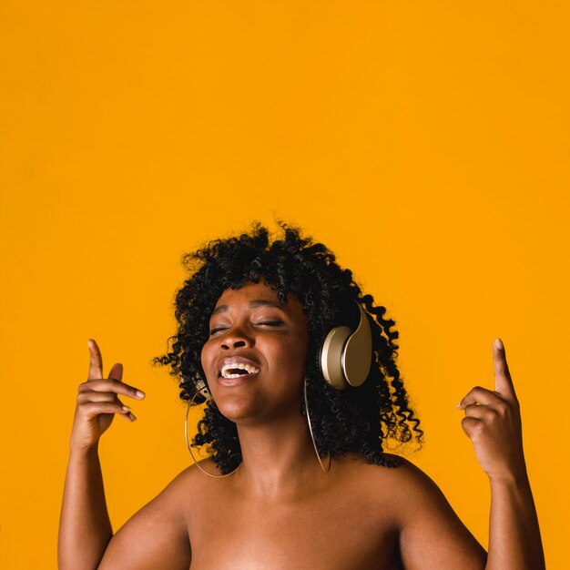 Hembra joven negra desnuda que canta en auriculares en estudio