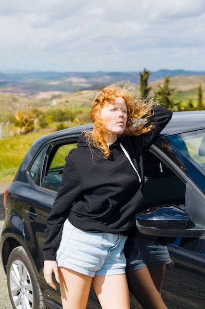 Hembra joven que se coloca cerca del coche negro