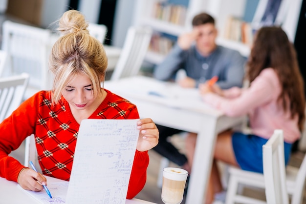 Foto gratuita hembra joven que estudia con el cuaderno en la biblioteca