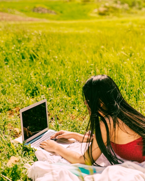 Hembra joven que practica surf en la computadora portátil en campo