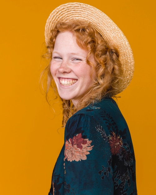 Hembra joven con sombrero y con pelo rizado sonriendo.