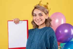 Foto gratuita hembra joven sosteniendo globos de colores y nota sobre amarillo