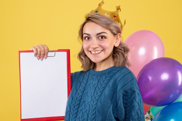 Hembra joven sosteniendo globos de colores y nota sobre amarillo