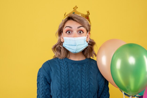 Hembra joven sosteniendo globos en máscara estéril en amarillo