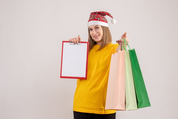 Foto gratuita hembra joven sosteniendo paquetes de compras y nota sobre blanco