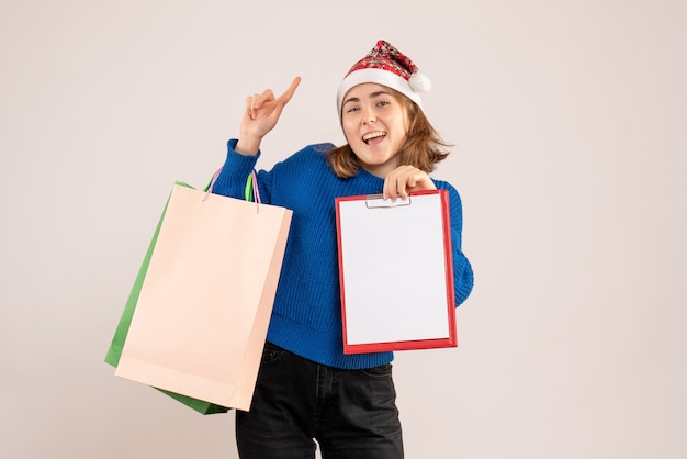 Hembra joven sosteniendo paquetes de compras y nota sobre blanco