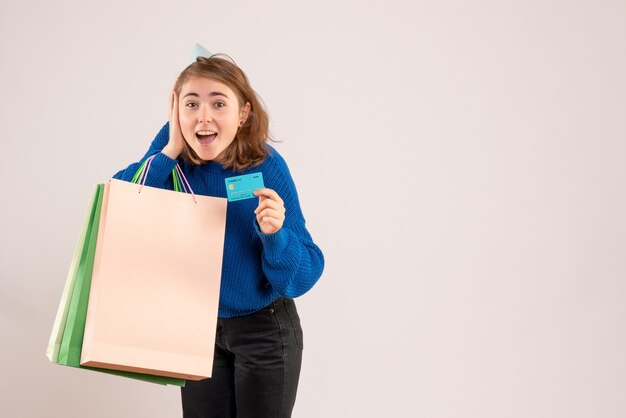 Hembra joven sosteniendo paquetes de compras y tarjeta bancaria en blanco