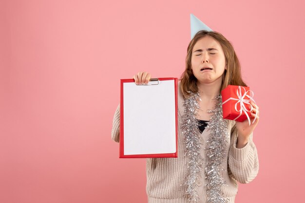 Hembra joven sosteniendo poco presente de Navidad y nota en rosa