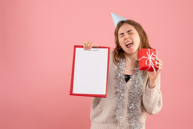 Hembra joven sosteniendo poco presente de Navidad y nota en rosa