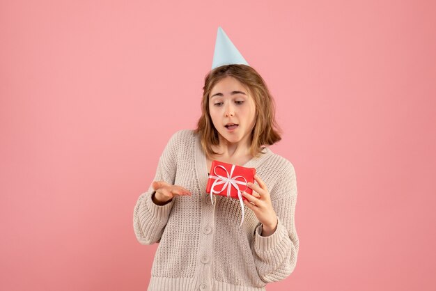 Hembra joven sosteniendo poco presente de Navidad en rosa