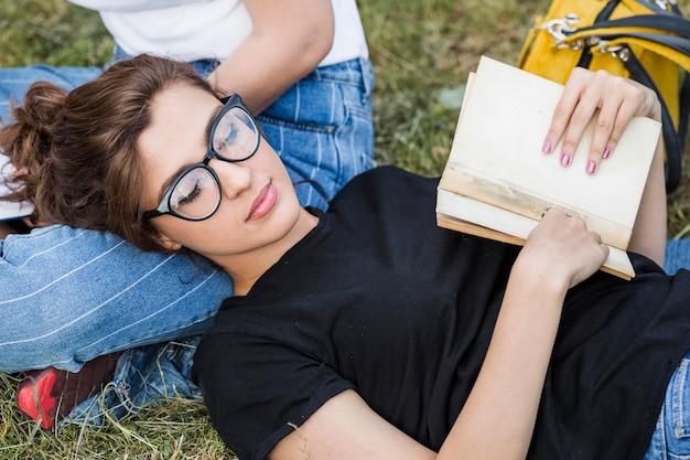 Foto gratuita hembra con el libro que duerme en hierba