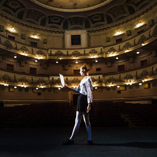 Hembra mime leyendo manuscrito en el auditorio vacío