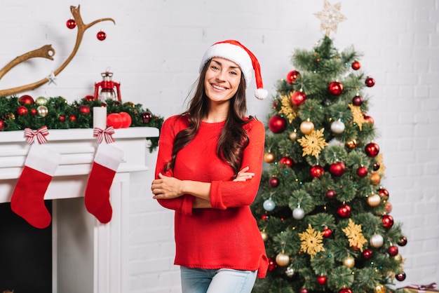 Hembra sonriente joven cerca del árbol de navidad