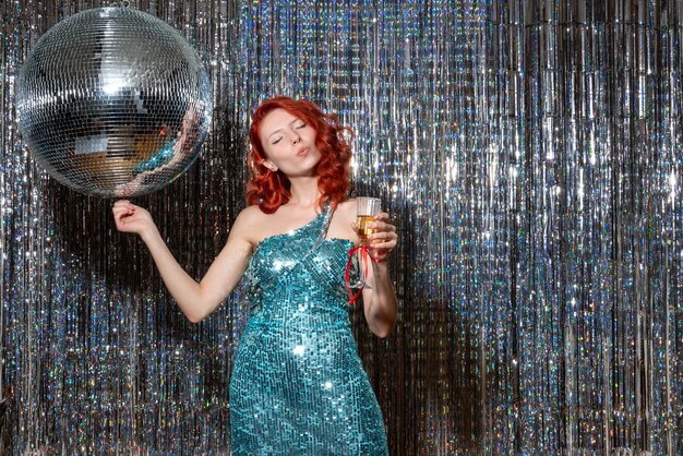 Las hembras jóvenes celebrando el año nuevo en la fiesta con bola de discoteca en cortinas brillantes