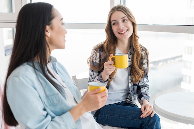 Hembras jóvenes sentadas con tazas