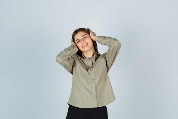 Las hembras jóvenes tomados de la mano en la cabeza en camisa y mirando feliz