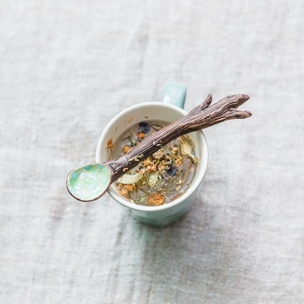 Herbal brew en taza con cuchara de madera