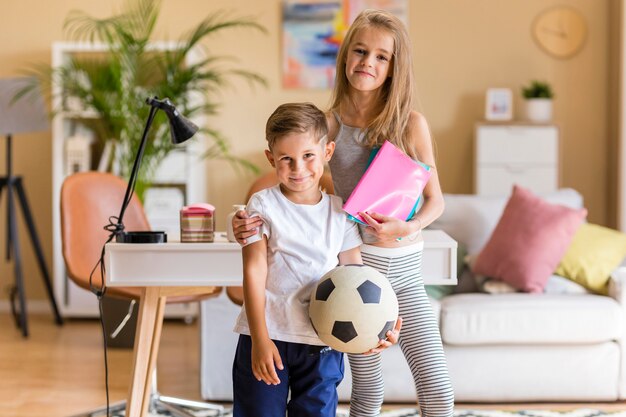 Hermana mayor y hermano con pelota de fútbol y cuadernos