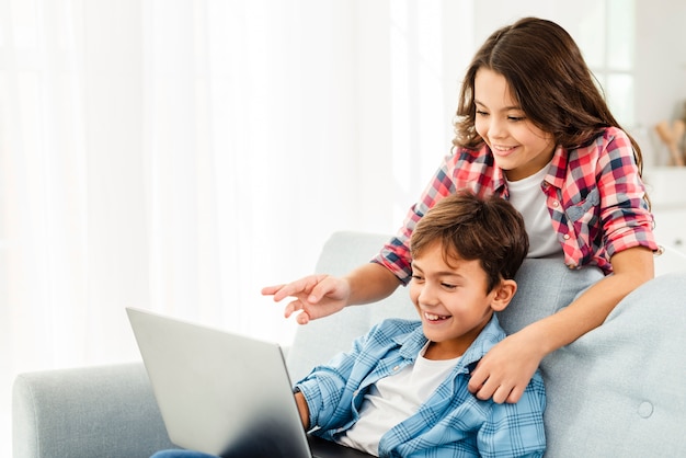 Hermana mostrando al hermano algo en la computadora portátil