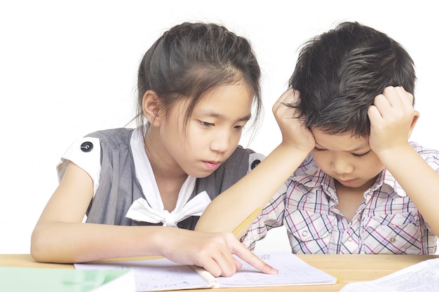 La hermana trata de enseñarle a su travieso hermano menor a hacer la tarea.