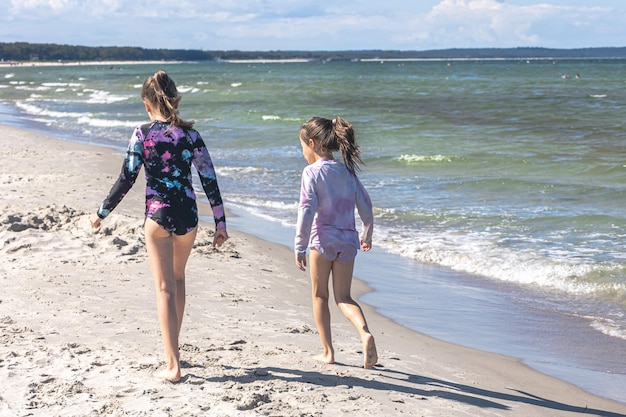 Las hermanas alegres de las niñas juegan en la orilla del mar