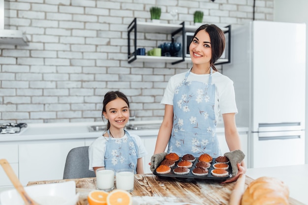 Hermanas hermosas jóvenes cocinan lote de cupcakes