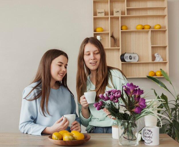 Hermanas hermosas jovenes que sostienen las tazas blancas