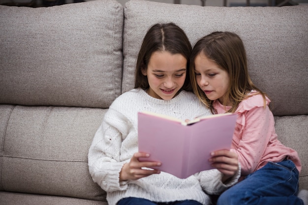 Foto gratuita hermanas leyendo libro juntas