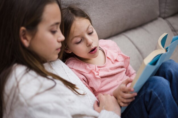 Hermanas leyendo libro juntas