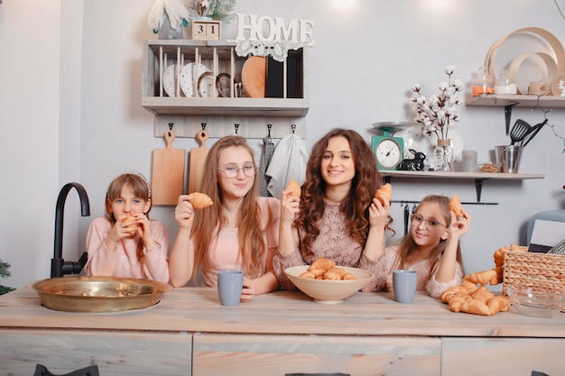 Hermanas lindas de pie en una cocina y come bollos