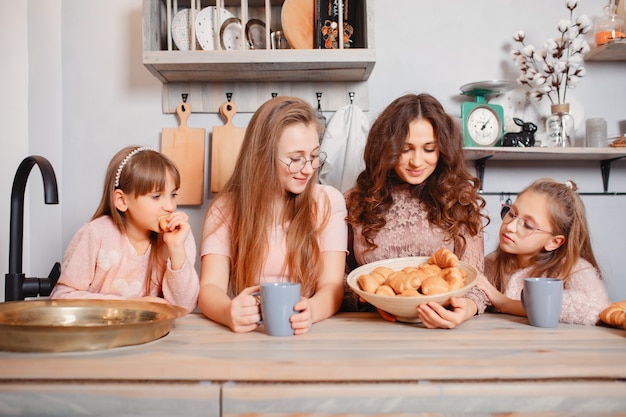 Hermanas lindas de pie en una cocina y come bollos