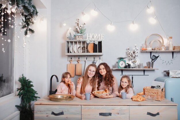 Hermanas lindas de pie en una cocina y come bollos