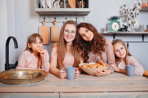 Hermanas lindas de pie en una cocina y come bollos