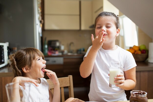 Hermanas sonrientes jugando mientras desayunando