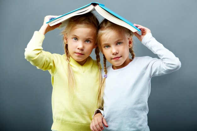 Hermanas usando un libro abierto como un paraguas